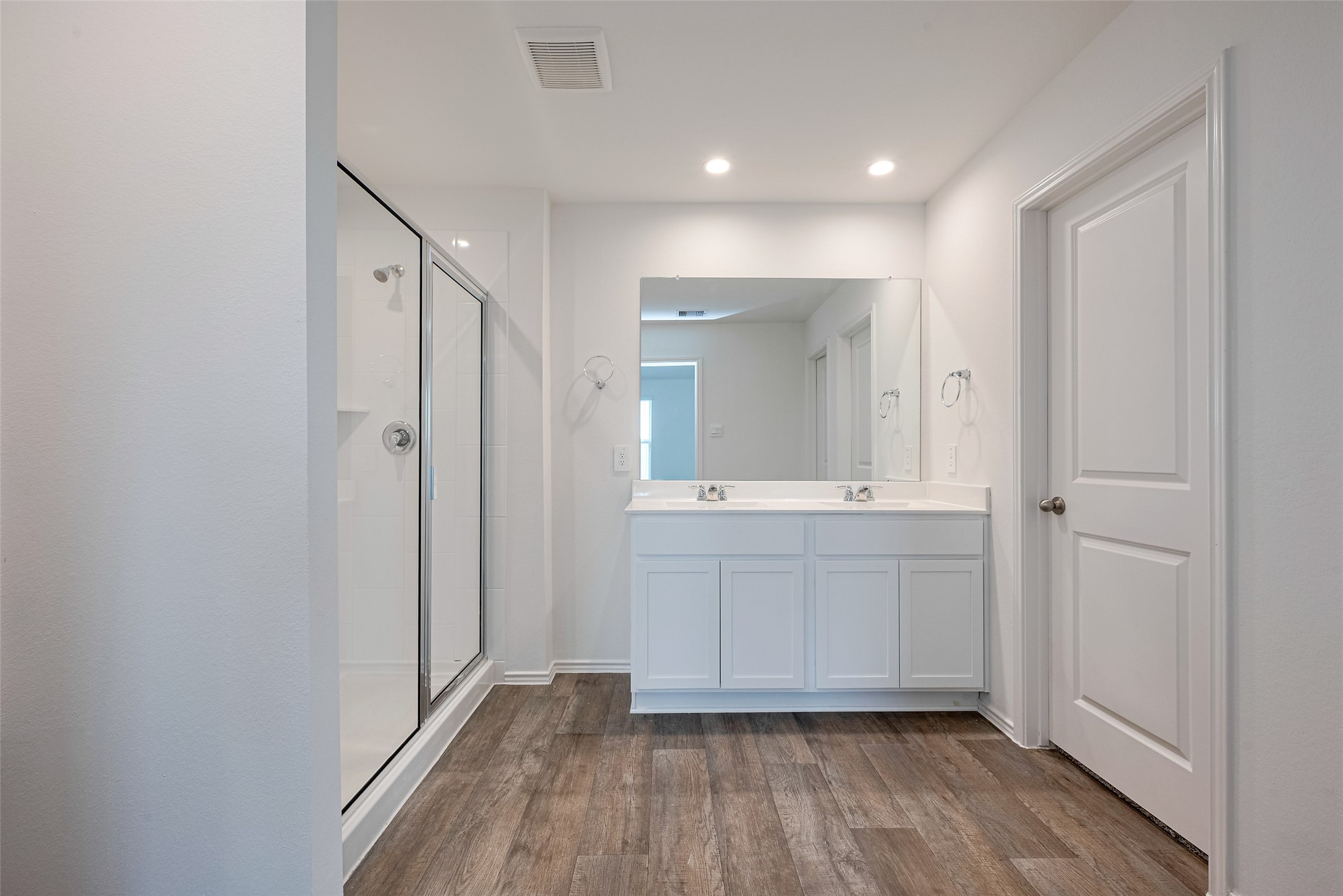 30910 Rockstock Road Fulshear, TX 77441 - Photo 27 of 33 The en suite bath offers a dual-sink vanity with polished white cabinetry and a broad mirror above. A separate enclosed shower completes the layout with practical elegance.