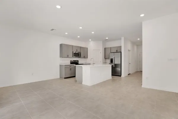a view of open kitchen with white cabinets and stainless steel appliances