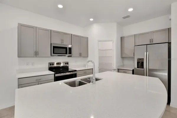 a kitchen with refrigerator a microwave a stove and white cabinets