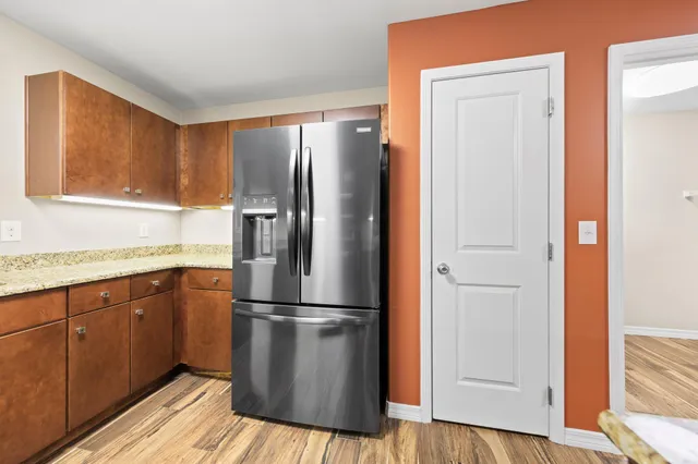 a kitchen with a refrigerator and wooden floor