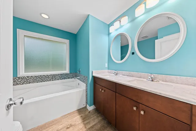 a bathroom with a bathtub mirror and sink