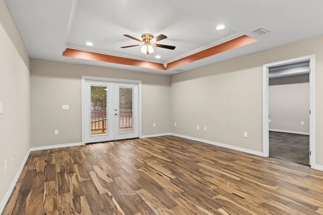 a view of an empty room with window and wooden floor