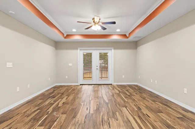a view of empty room with wooden floor and fan