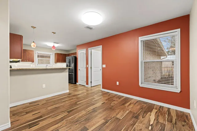 a view of an empty room with kitchen and a window