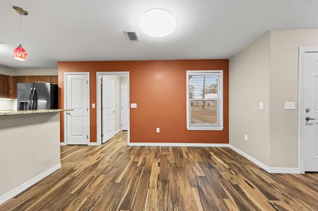 a view of an empty room with wooden floor and a window
