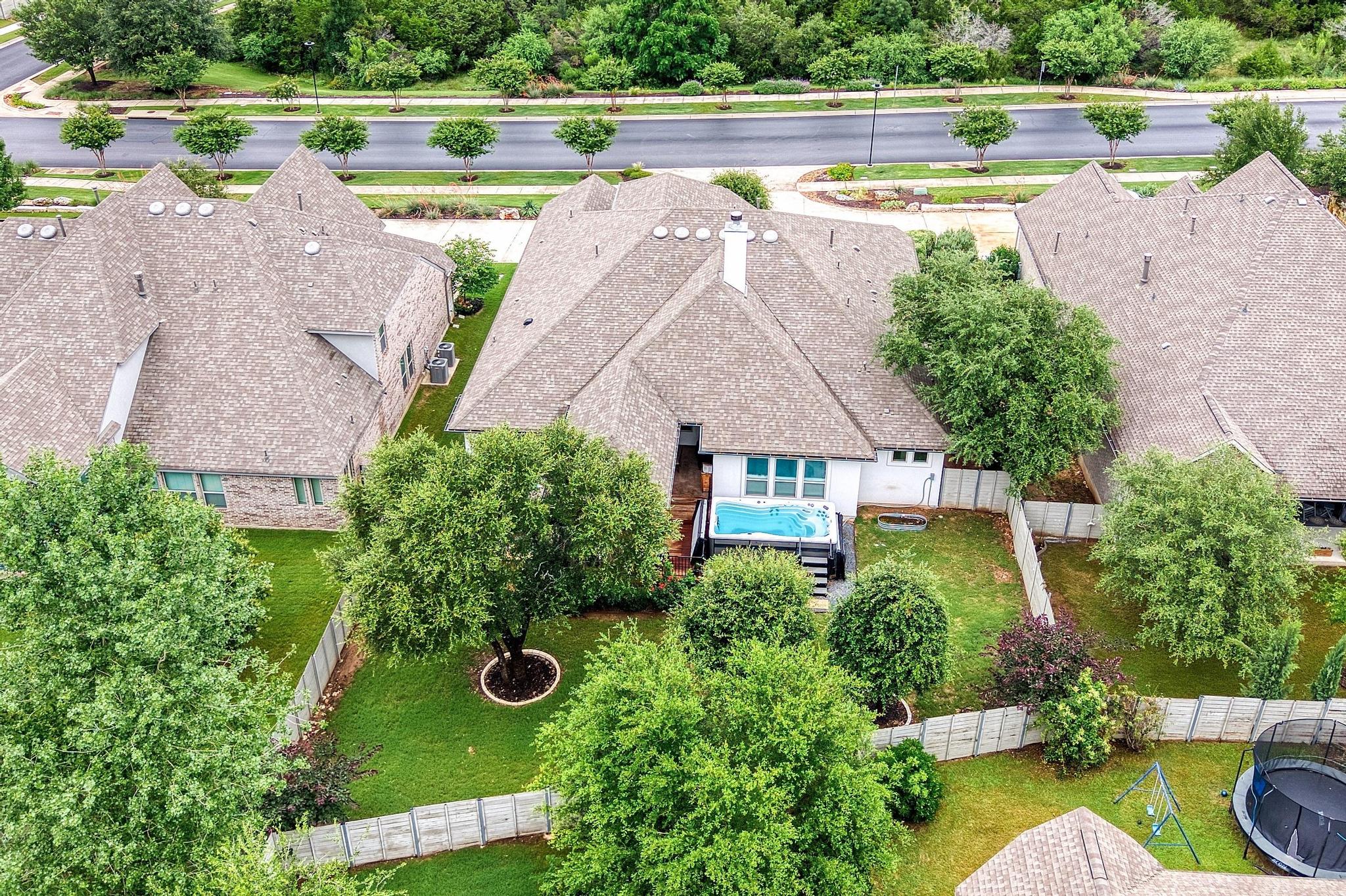 1009 Legacy Crossing Georgetown, TX 78628 - Photo 2 of 40 An aerial perspective reveals a cozy private yard with a spa, nestled among verdant trees and neighboring homes.