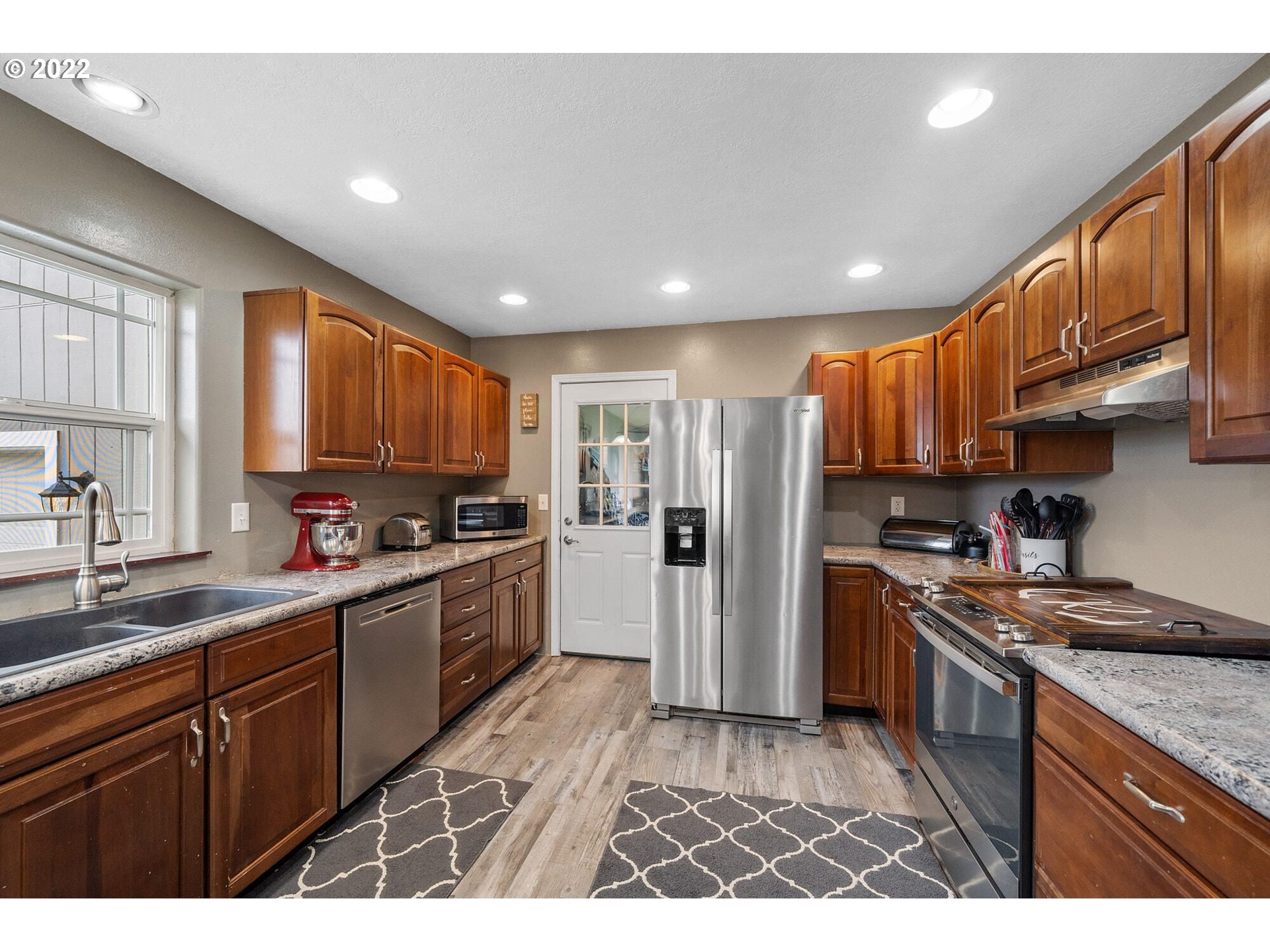 3895 Gienger Road Tillamook, OR 97141 - Photo 4 of 25 a kitchen with stainless steel appliances granite countertop a refrigerator a sink dishwasher a stove and white cabinets with wooden floor