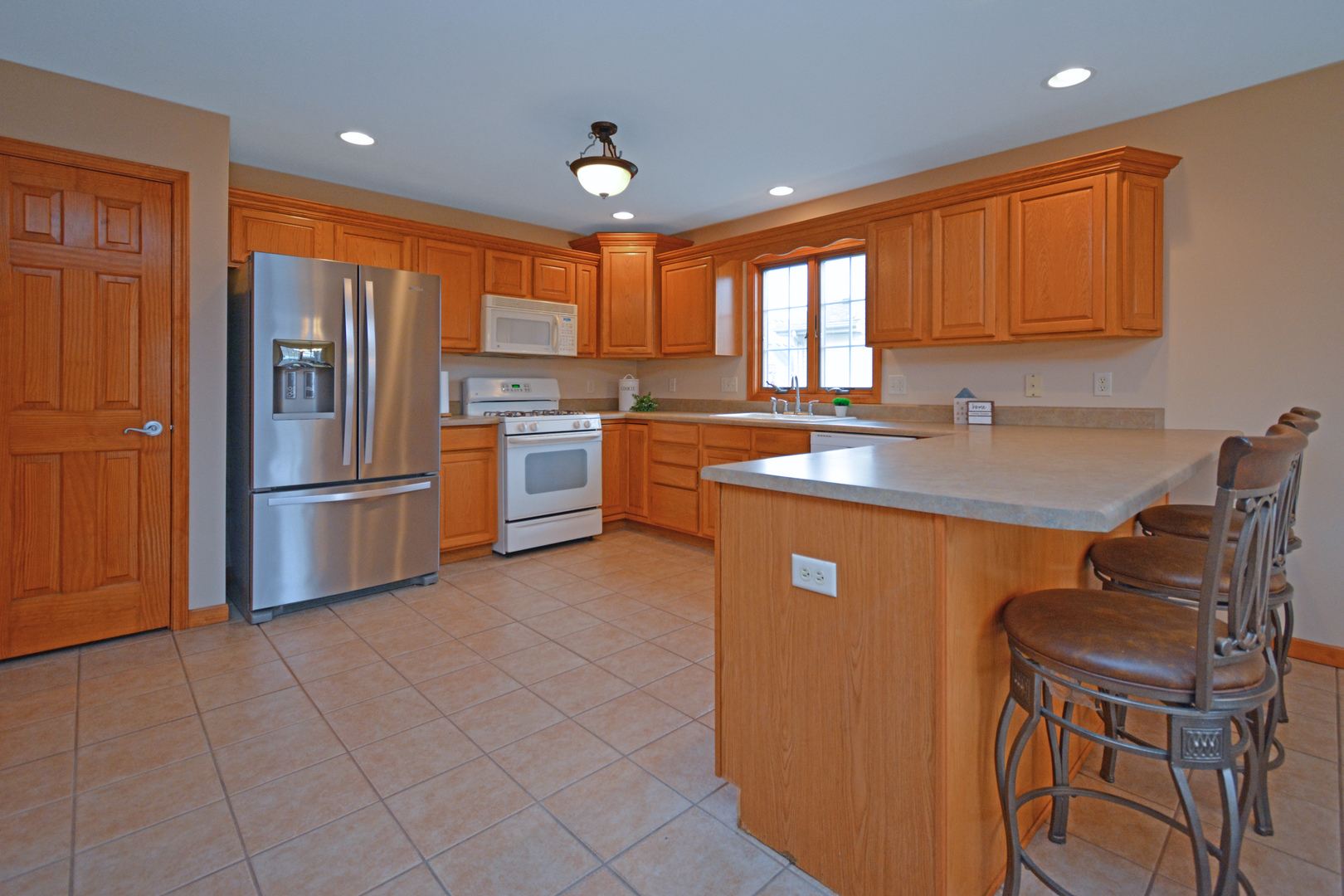 2884 Bear Claw Street Normal, IL 61761 - Photo 15 of 62 a kitchen with stainless steel appliances granite countertop a refrigerator a sink dishwasher a stove a dining table and chairs with wooden floor