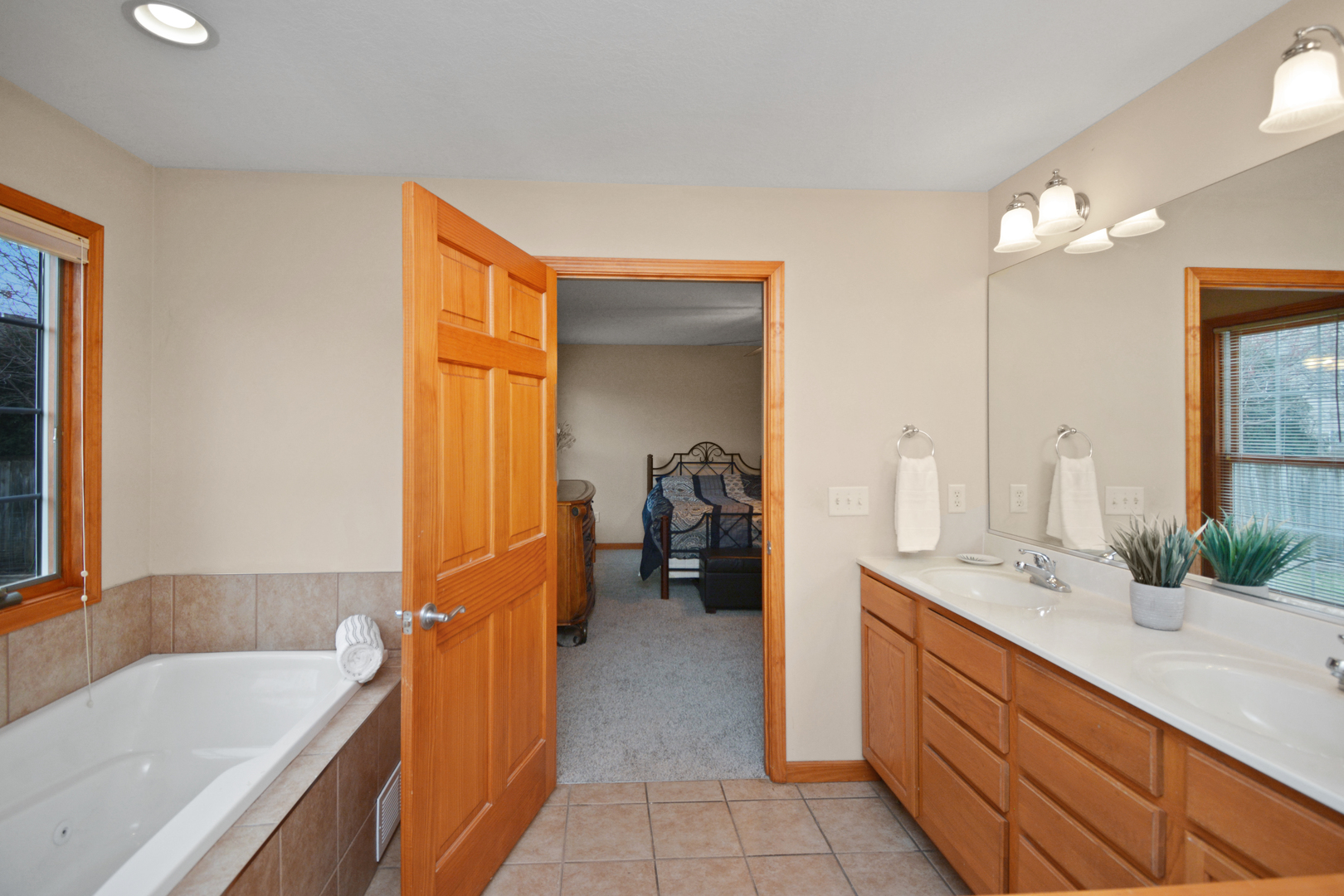 2884 Bear Claw Street Normal, IL 61761 - Photo 35 of 62 a bathroom with a double vanity sink a mirror and a bathtub