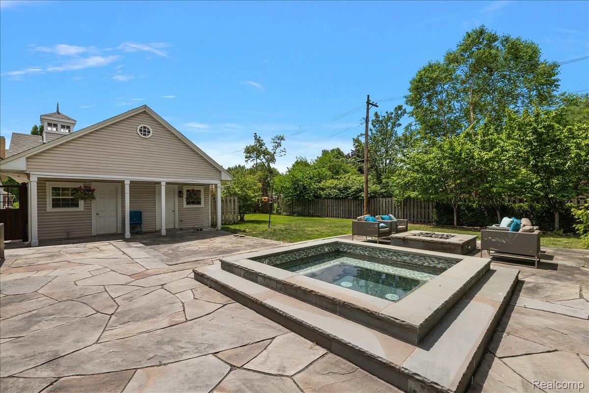 1051 Devonshire Road Grosse Pointe, MI 48230 - Photo 80 of 99 Expansive flagstone patio featuring a built-in spa with tiled surround, a fire pit area, and mature perimeter trees