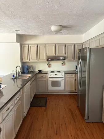 a kitchen with stainless steel appliances granite countertop a white cabinets a sink a stove a refrigerator and a microwave