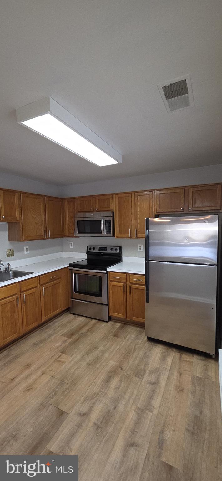 11192 Rienzi Place, Unit 102 Manassas, VA 20109 - Photo 6 of 19 a kitchen with stainless steel appliances kitchen island granite countertop a stove and a sink