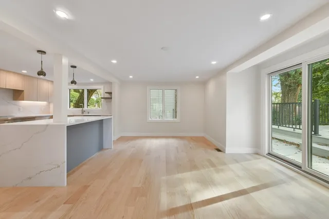 a view of an empty room with kitchen and window
