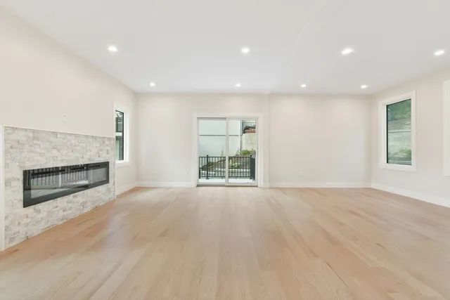 an empty room with wooden floor fireplace and windows