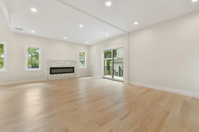 an empty room with wooden floor fireplace and windows