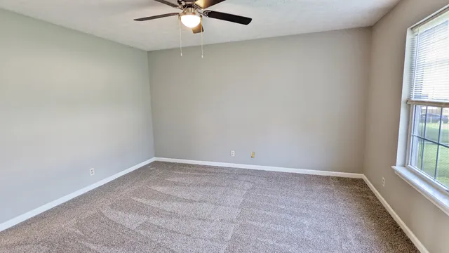 an empty room with windows and fan