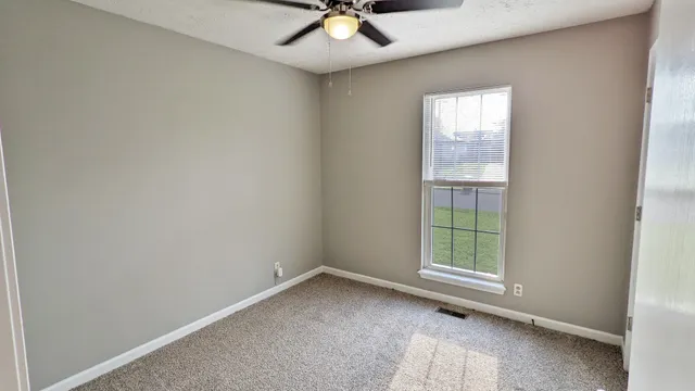 an empty room with a window and a fan