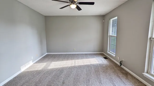 an empty room with a window and a ceiling fan