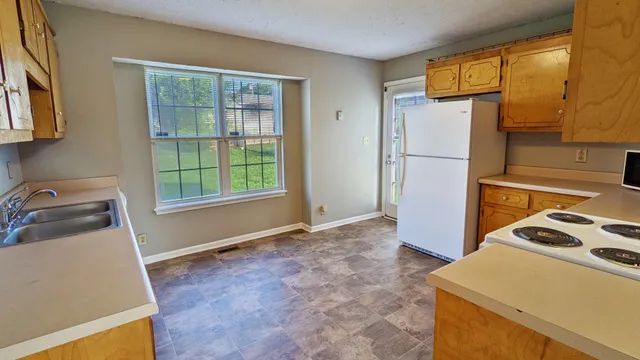 a view of a kitchen with fridge and wooden floor