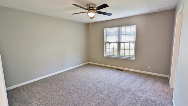 an empty room with a window and a fan