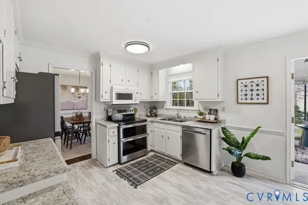 a kitchen with stainless steel appliances granite countertop a stove top oven a sink a dining table and chairs