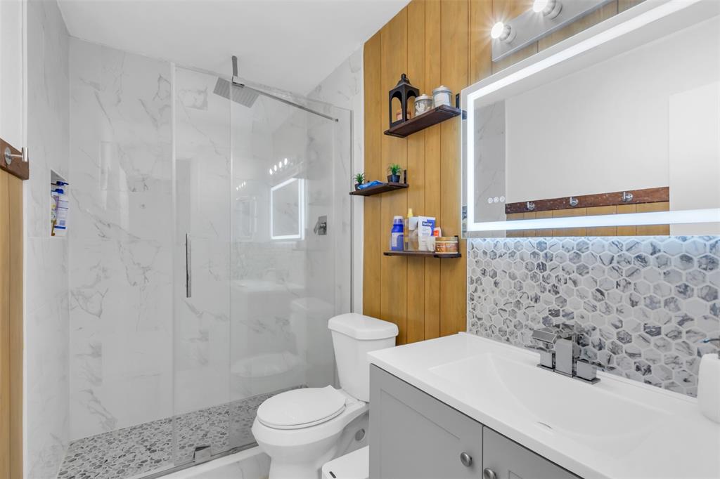 7670 Kings Ridge Road Frisco, TX 75035 - Photo 19 of 24 Bathroom featuring vanity, a marble finish shower, and decorative backsplash