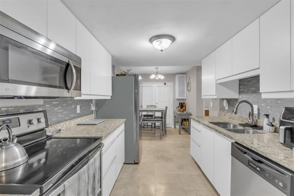 7670 Kings Ridge Road Frisco, TX 75035 - Photo 6 of 24 Kitchen featuring stainless steel appliances, tasteful backsplash, light stone countertops, and white cabinetry