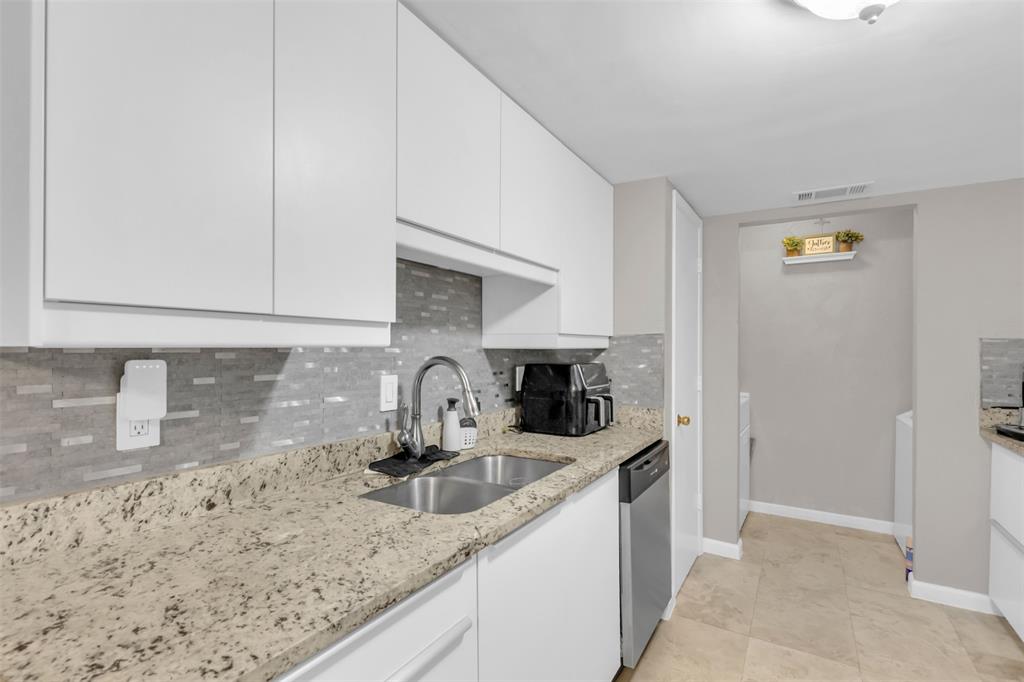 7670 Kings Ridge Road Frisco, TX 75035 - Photo 7 of 24 Kitchen featuring tasteful backsplash, white cabinetry, light stone countertops, and light tile patterned floors