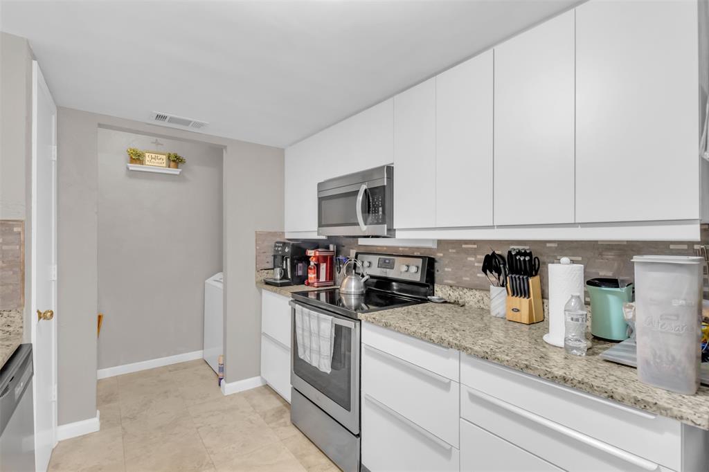 7670 Kings Ridge Road Frisco, TX 75035 - Photo 9 of 24 Kitchen featuring appliances with stainless steel finishes, white cabinets, decorative backsplash, modern cabinets, and light stone counters