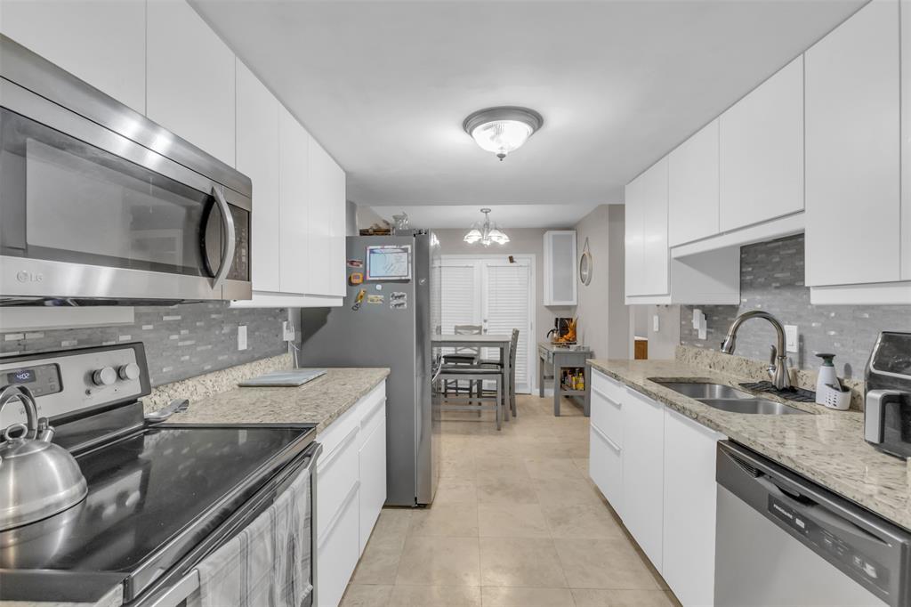 7670 Kings Ridge Road Frisco, TX 75035 - Photo 10 of 24 Kitchen featuring stainless steel appliances, tasteful backsplash, light stone counters, and white cabinets