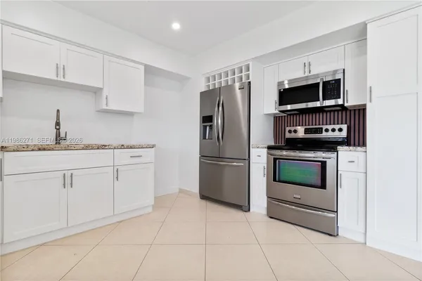 a kitchen with stainless steel appliances granite countertop a refrigerator and a stove top oven