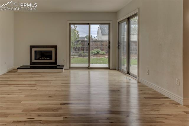 620 Gilcrest Road Colorado Springs, CO 80906 - Photo 6 of 17 Hickory flooring, gas fireplace, marble hearth, 2 walk-outs to the gorgeous landscaped backyard.