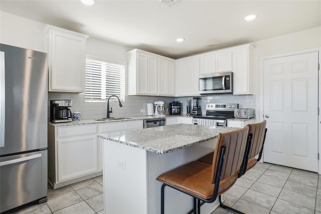 1719 Ackerly Drive Forney, TX 75126 - Photo 5 of 27 a kitchen with stainless steel appliances granite countertop a stove a sink a refrigerator a microwave a refrigerator and cabinets