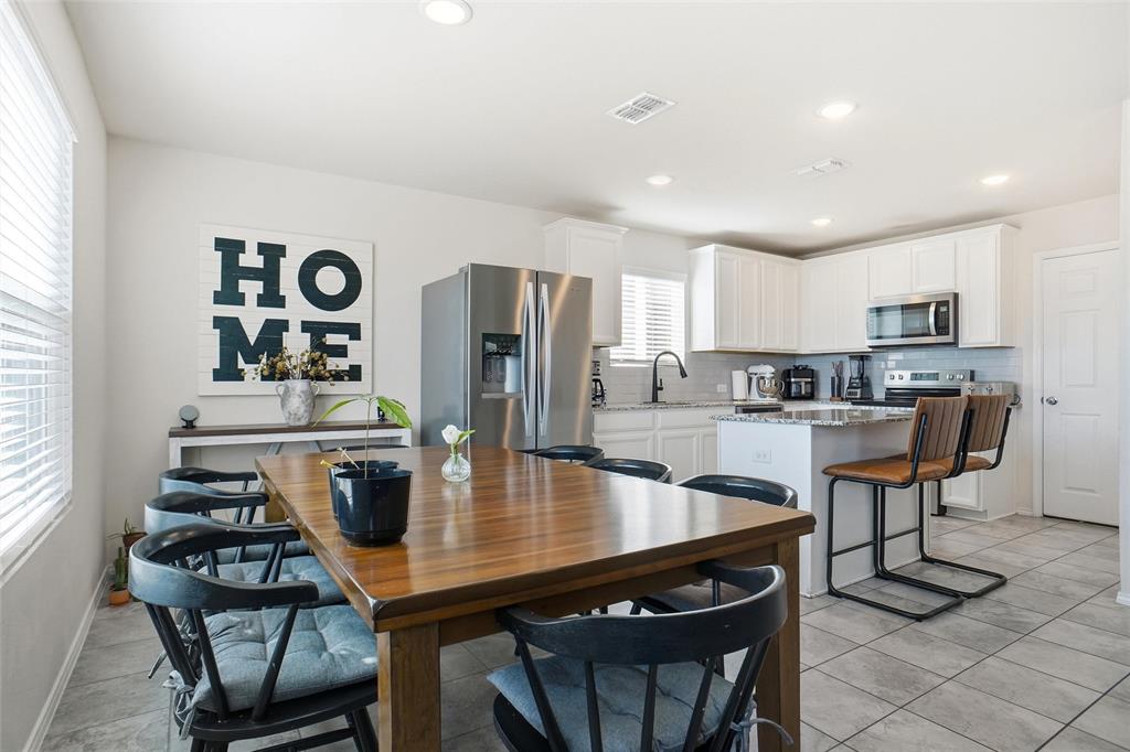 1719 Ackerly Drive Forney, TX 75126 - Photo 6 of 27 a kitchen with stainless steel appliances granite countertop a stove a refrigerator a sink a table and chairs