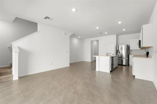 a view of kitchen with refrigerator and white cabinets
