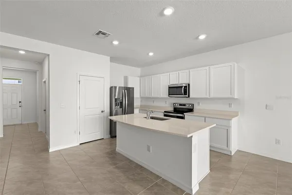 a kitchen with a sink a refrigerator a stove top oven and white cabinets