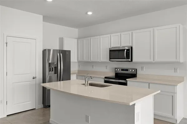 a kitchen with stainless steel appliances a sink a stove a microwave a refrigerator a counter space and cabinets