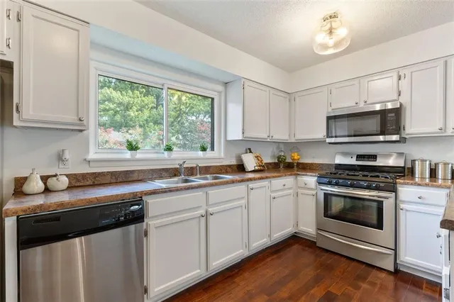 a kitchen with stainless steel appliances granite countertop a sink a stove a microwave and wooden cabinets
