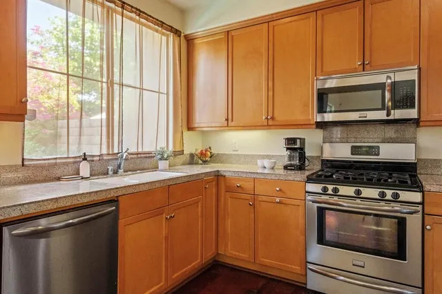 a kitchen with stainless steel appliances granite countertop a stove a sink and a microwave