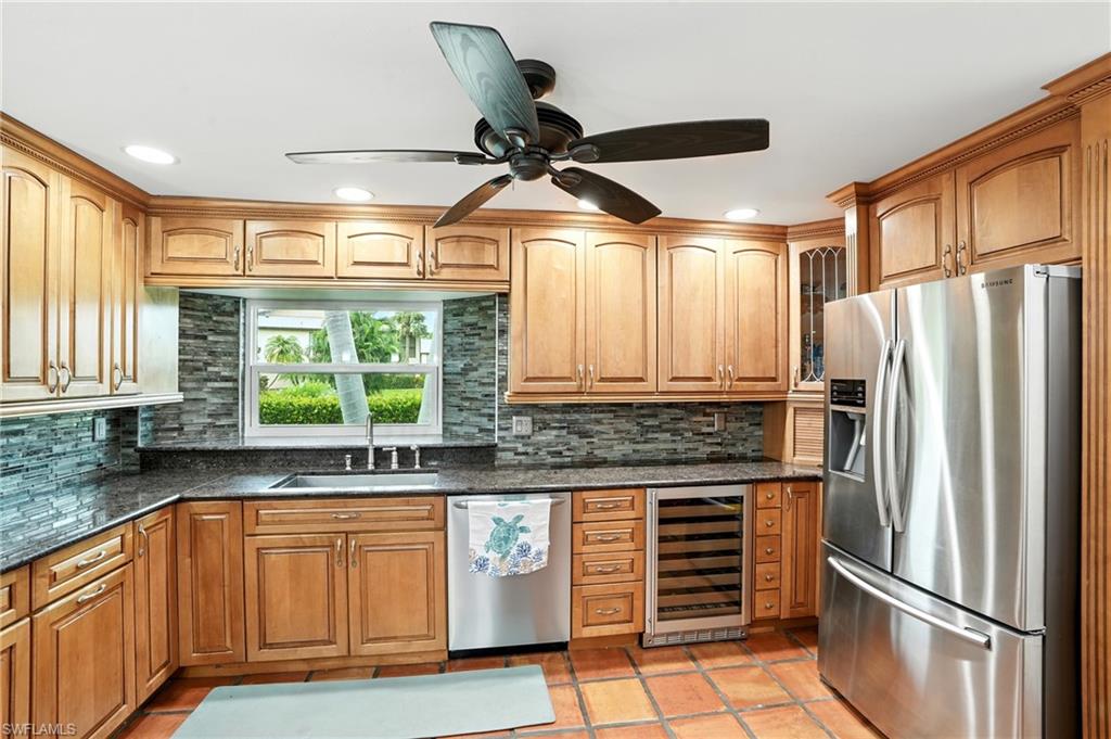 249 Pebble Beach Circle Naples, FL 34113 - Photo 15 of 45 Kitchen featuring stainless steel appliances, glass insert cabinets, wine cooler, dark stone countertops, and recessed lighting
