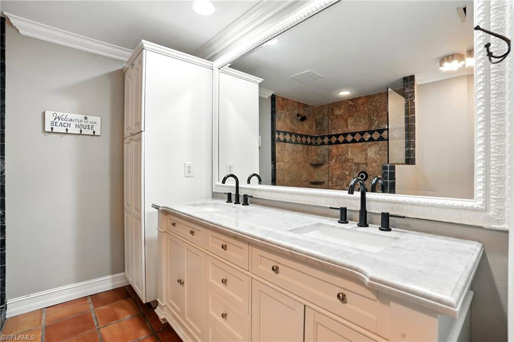249 Pebble Beach Circle Naples, FL 34113 - Photo 27 of 45 Bathroom featuring crown molding, tiled shower, double vanity, and dark tile patterned floors