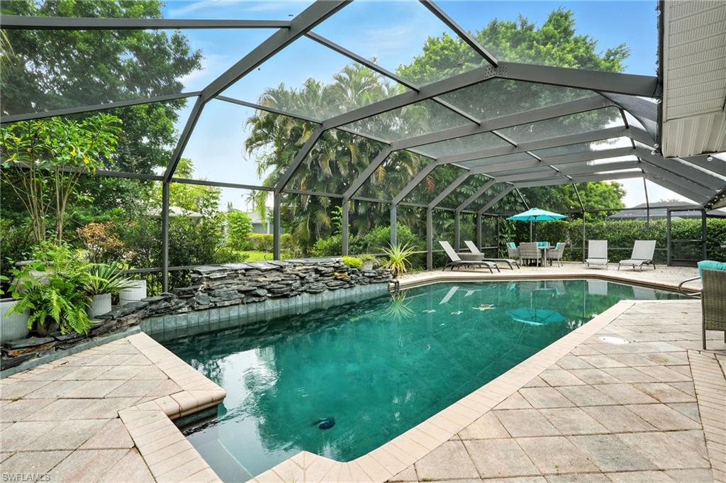 249 Pebble Beach Circle Naples, FL 34113 - Photo 3 of 45 Swimming pool with glass enclosure, a sunroom, and a patio