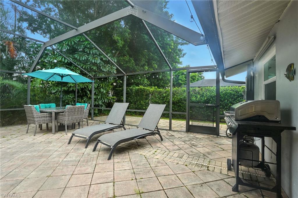 249 Pebble Beach Circle Naples, FL 34113 - Photo 38 of 45 View of patio / terrace with glass enclosure, a sunroom, a grill, and outdoor dining space