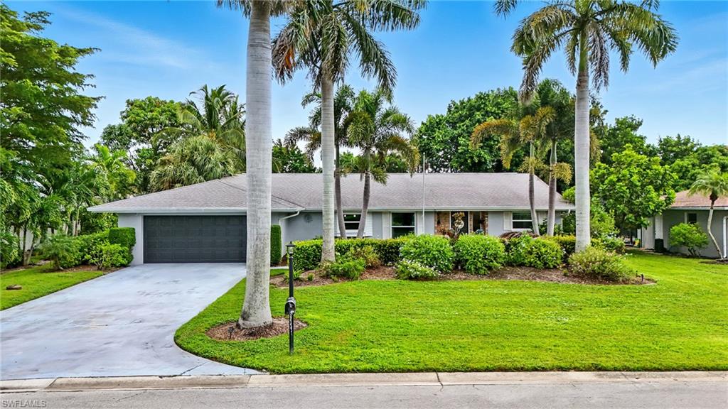 249 Pebble Beach Circle Naples, FL 34113 - Photo 41 of 45 Single story home featuring driveway, a front yard, an attached garage, roof with shingles, and stucco siding