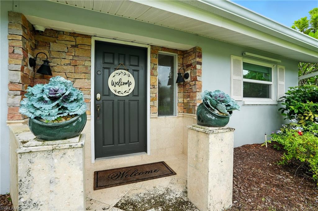 249 Pebble Beach Circle Naples, FL 34113 - Photo 6 of 45 Doorway to property with stone siding, a porch, and stucco siding