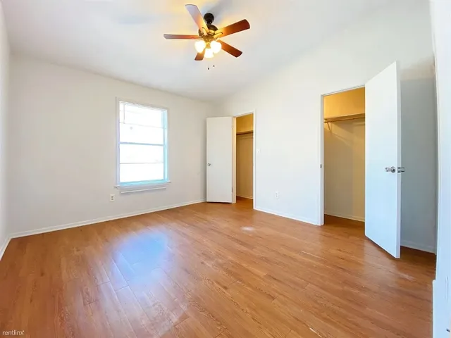 a view of empty room with wooden floor and fan