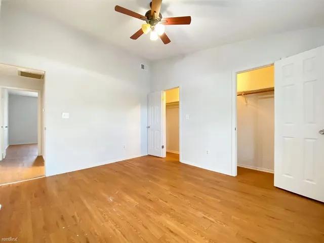 a view of a big room with wooden floor and a chandelier fan