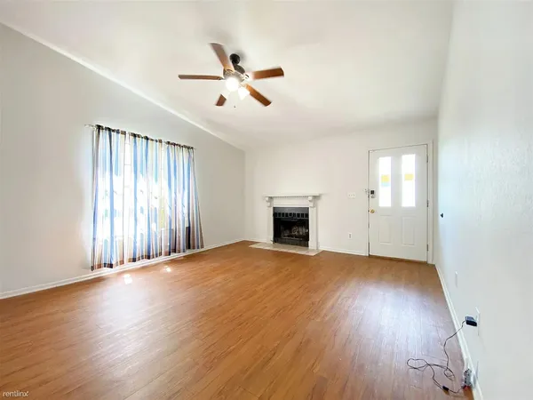 an empty room with wooden floor fan and windows