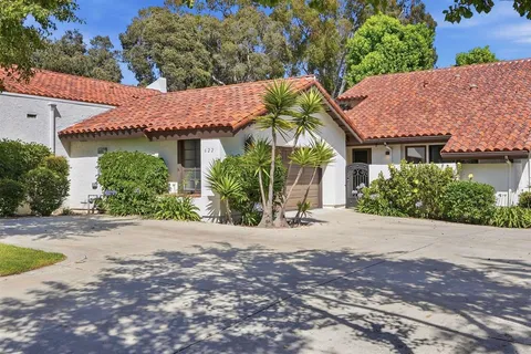 a view of a house with a yard and potted plants
