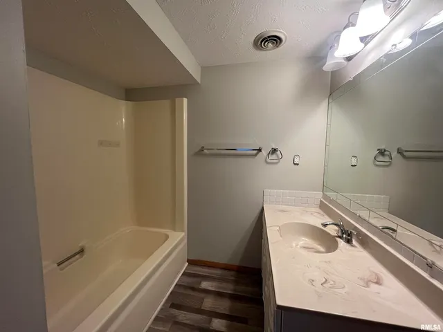 a bathroom with a tub a sink and mirror